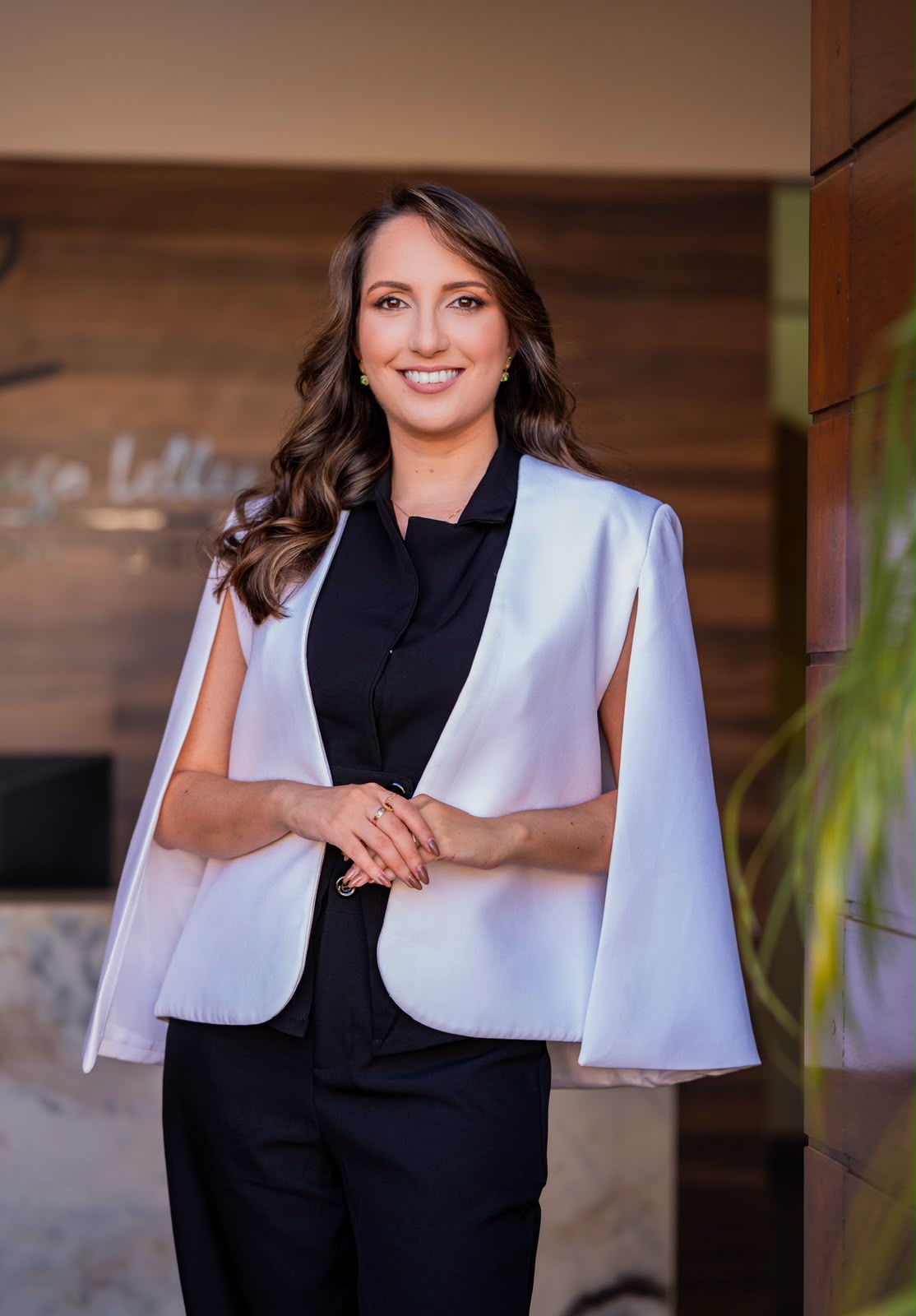 Maria Caroline de Melo Araújo, advogada tributarista, com blazer branco e sorriso acolhedor.